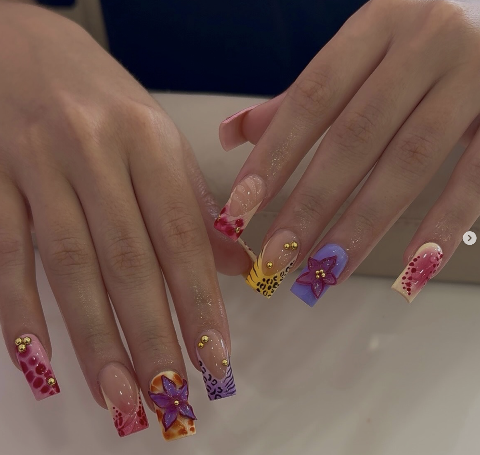 Colorful nail art with gold studs and floral patterns